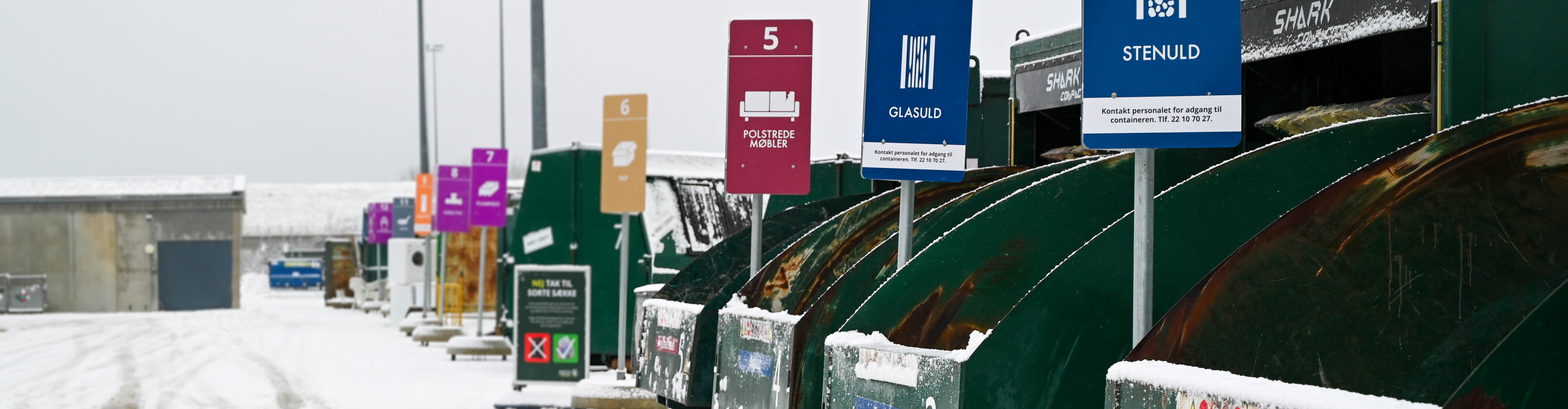 Skilte på genbrugspladsen i snevejr.